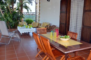 A dining area with a wooden table, chairs, and a bowl of salad. There are potted plants and a white cabinet in the background. - Posh Villa Carla with private pool, near the beach (Balestrate)