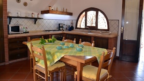 A dining area with a wooden table and chairs, a microwave, and a coffee maker on the counter.