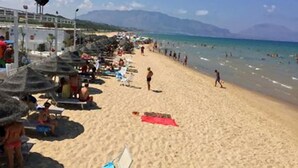 A beach with umbrellas and people.