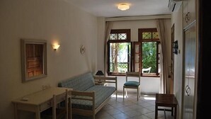 Une pièce comprenant un lit, un bureau, une chaise et une fenêtre avec des rideaux.
