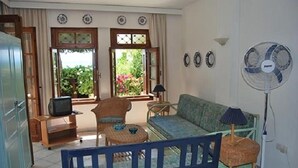 Un salon avec un canapé, des fauteuils, un téléviseur et un ventilateur.