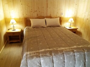 Una stanza con pannelli di legno, un letto, due lampade da comodino e un comodino.