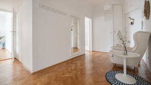 A spacious room with a wooden herringbone floor, a white wall, and a large mirror. - STATE OPERA SUITE CITY CENTER "Santorini" (Wien)
