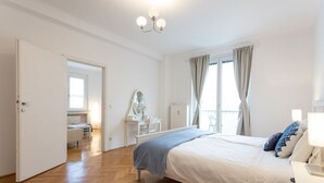 A bedroom with a large bed, a desk, a chair, and a window with curtains. - STATE OPERA SUITE CITY CENTER "Santorini" (Wien)