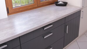 A kitchen with a window, a white cabinet, and a black basket on the counter. - Comfort apartment with open fireplace 3 *** (Kandern)