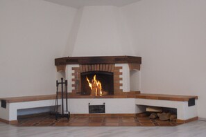 A fireplace with a brick surround and a mantel, with logs stored underneath.
