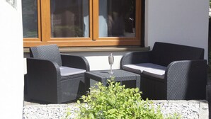A patio area with wicker furniture, a glass table, and a small plant. - Comfort apartment with open fireplace 3 *** (Kandern)