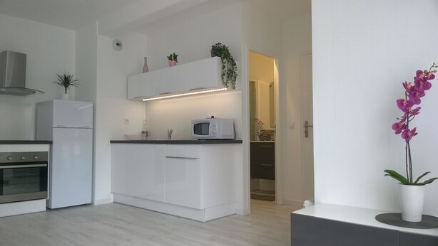 Una cocina moderna con gabinetes blancos, un microondas y una pequeña planta en la encimera.