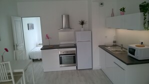 Cocina compacta con estufa, horno y microondas. Cuenta con un pequeño comedor con mesa y sillas.