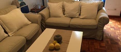 A living room with two beige sofas, a coffee table with lemons, and a wooden parquet floor.