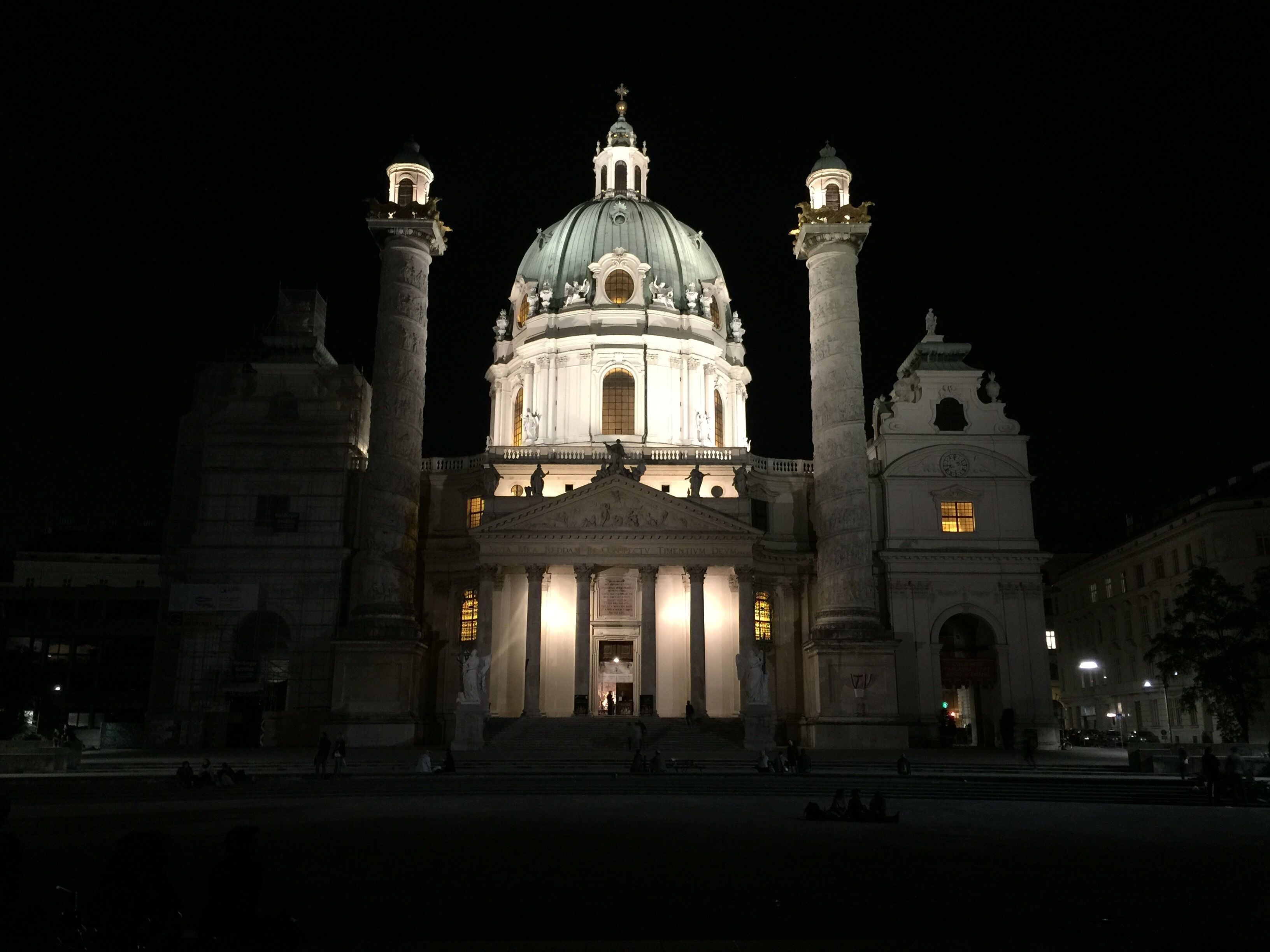 A grand building with a large dome and two tall columns, illuminated at night.