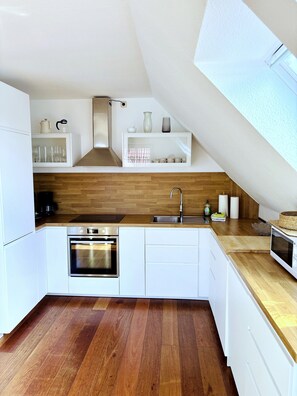 A modern kitchen with white cabinetry, a wooden countertop, and a built-in oven.