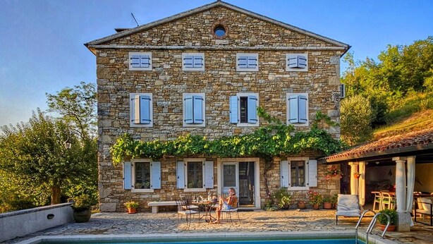 Un bâtiment en pierre avec une piscine devant.