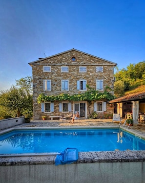 Un bâtiment en pierre avec une piscine devant.