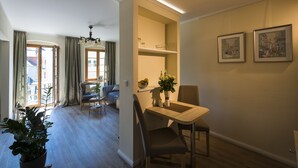 Un coin repas avec une table et des chaises, une plante en pot et une vue sur le salon.