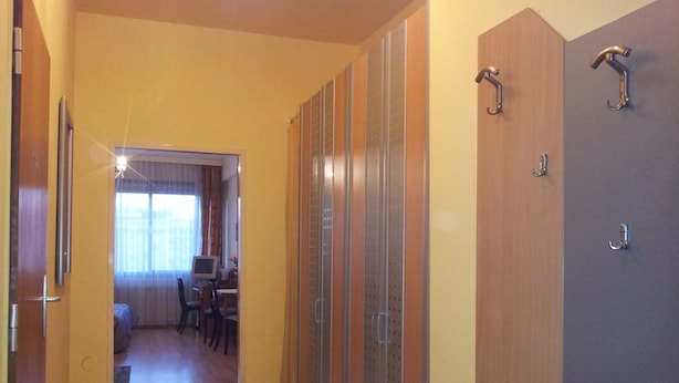 A hallway with wooden flooring, a dining area with a table and chairs, and a door with a metal handle. - Apartment City Center 2 (Wien)