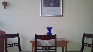 A dining area with a table, two chairs, a framed picture, and a vase. - Apartment City Center 2 (Wien)