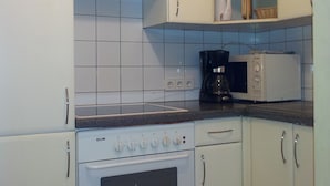 A kitchen with white cabinets, a stove, a microwave, and a coffee maker. - Apartment City Center 2 (Wien)