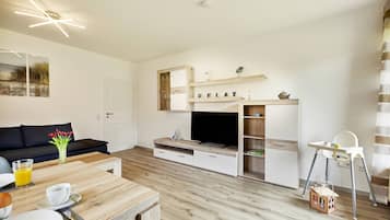 Relax in this stylish living room with a dining table, sofa, flat-screen TV, and high chair.