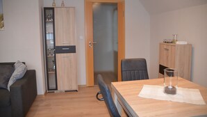 A compact living space with a kitchenette, a dining area with a table and chairs, and a sofa.
