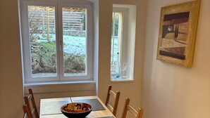 A dining area with a wooden table and chairs, a bowl on the table, and a painting on the wall. - tastefully furnished & quiet apartment in West Lichterfelde (Berlin)