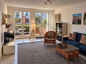 A living room with a sofa, a chair, a television, and a glass coffee table.