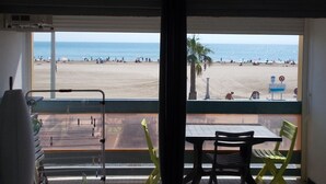 Une pièce avec vue sur la plage, une table avec des chaises et une fenêtre donnant sur la plage.