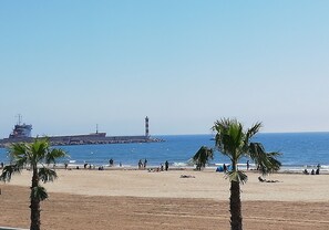 Una playa con palmeras, un faro y un barco al fondo.