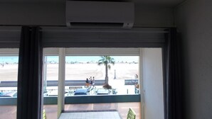 Une chambre avec vue sur la plage, un appareil de climatisation et un banc à l’extérieur.