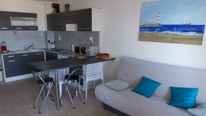 Un espace de vie compact comprenant un coin cuisine, un coin repas et un canapé avec des coussins.