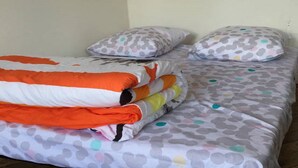 A bed with a polka dot bedspread and pillows, a stack of folded blankets, and a plain wall. - BEAUTIFUL APARTMENT 2 STEPS FROM THE BEACH / NEAR TO THE BEACH! (Étretat)