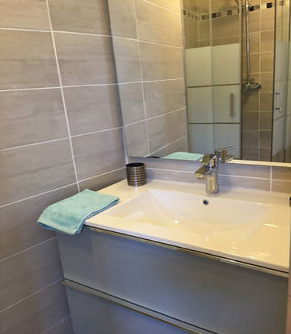 A bathroom with a white sink, a mirror, and a towel on the counter.