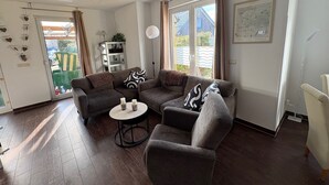 Ein modernes Wohnzimmer mit einer Eckcouch, einem runden Couchtisch und einem Deckenventilator.