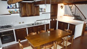 Une cuisine avec une table et des chaises en bois, une cuisinière, un four et un évier.