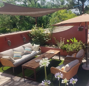 An outdoor patio with a sofa, chairs, a table, and a pergola.