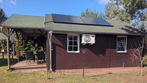 Un edificio con paneles solares, un patio cubierto y una ventana con unidad de aire acondicionado.