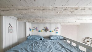 A bedroom with a bed, pillows, a wall clock, and a string of colorful balls. - charming studio in the heart of the old town (Annecy)
