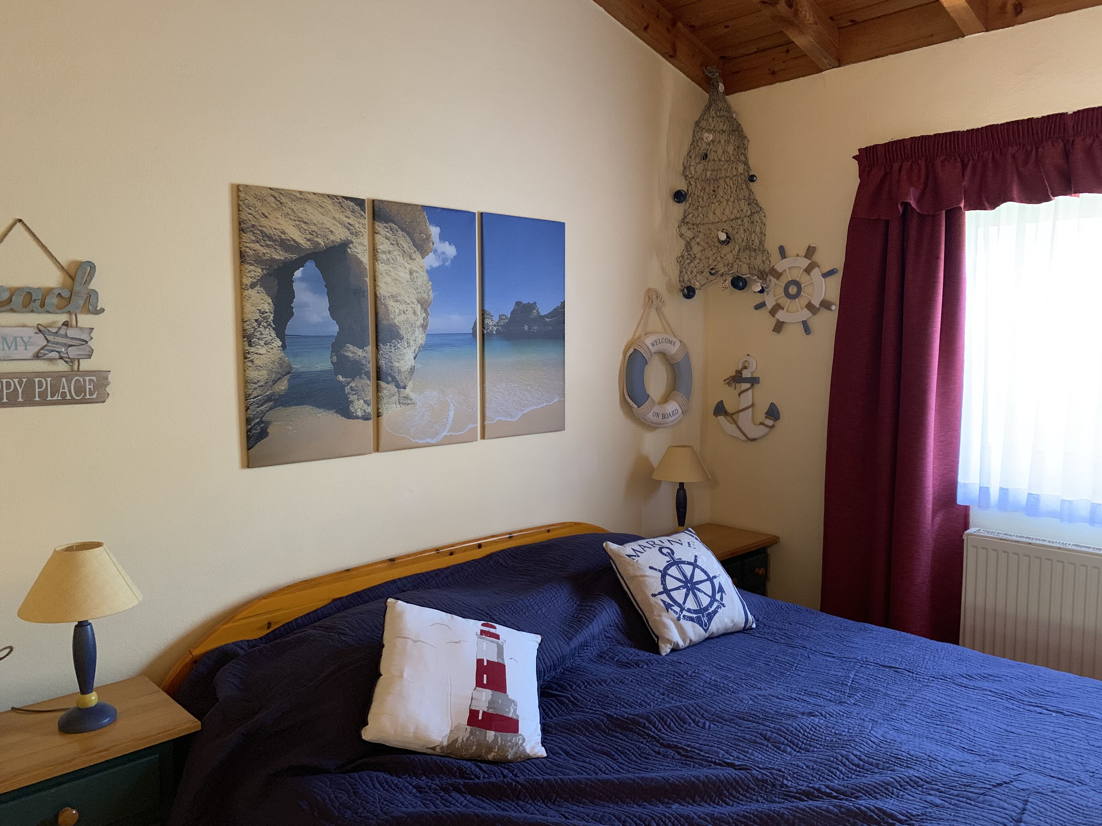 A bedroom with a bed, a nightstand, a lamp, and nautical-themed decorations.