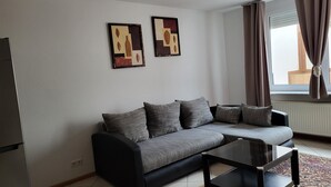 A modern living room with a grey sofa, a glass coffee table, and two abstract paintings on the wall. - Away from the city life and yet part of the action (Appenweier)