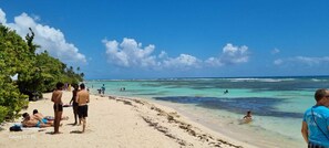 A beach with people sunbathing and swimming. - ROOM FOR TOURISM (MORNE A L'EAU)