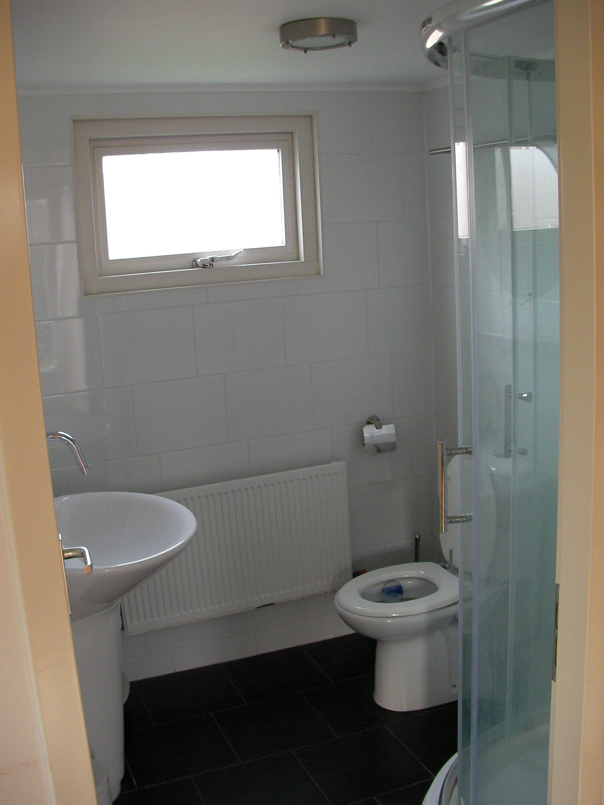 Une salle de bain avec un lavabo blanc, des toilettes et une douche à parois de verre.