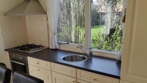 A kitchen with a gas stove, sink, and window overlooking a garden.