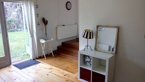 A room with wooden flooring, a white console table with a lamp, a mirror, and a radiator.