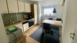 Una cocina compacta con comedor, horno integrado y ventana con plantas.
