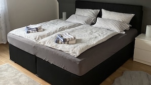 Un dormitorio moderno con una cama grande, un cabecero oscuro y una pared de acento gris.