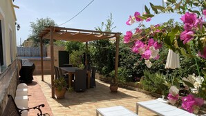 Une terrasse dotée d’une pergola, de mobilier d’extérieur et de plantes en pot.