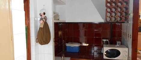 Una cocina con microondas, un lavabo y una estantería con frascos.
