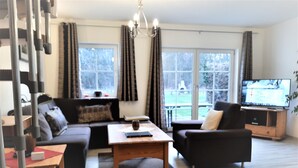 A living room with a sofa, armchair, coffee table, and a TV on a wooden stand. - Vacation for the family. Top apartment**** 2-4 persons, 75sqm, terrace. 2 bedrooms.  (Walkenried / Südharz)