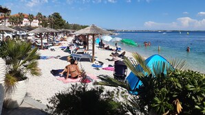 A beach scene with umbrellas, lounge chairs, and people relaxing on the sand.