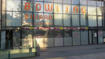 En byggnad med stora glasfönster där det står "BOWLING BILLIARD" och "SALLE CLIMATISEE".